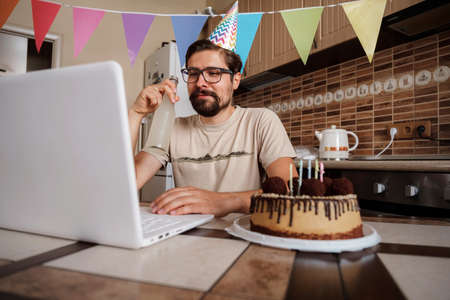 Man celebrating birthday online in quarantine time. Video conference party online meeting with friends and family. Birthday party in video call. Long Distance Celebration.の写真素材