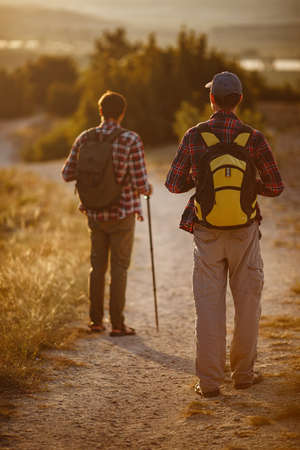 two men hikers enjoy a walk in nature, sunset time in summer. enjoying their adventure. Lifestyle hiking concept vacations outdoorの写真素材
