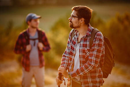two men hikers enjoy a walk in nature, sunset time in summer. enjoying their adventure. Lifestyle hiking concept vacations outdoorの写真素材