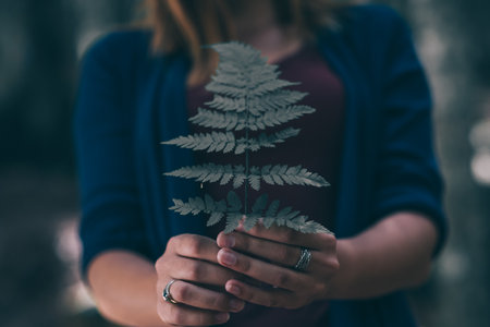 happy young woman, with fern leaf in hands in the forestの写真素材