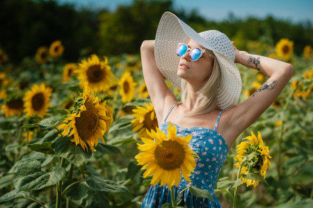 beautiful sweet sexy girl in a blue dress walking on a field of sunflowers, smiling a beautiful smile, cheerful girl, style, lifestyle, ideal for advertising and photo sun shines bright and juicyの写真素材