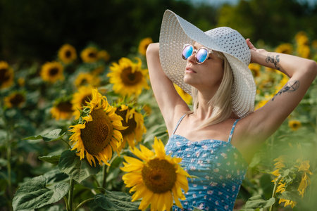 beautiful sweet sexy girl in a blue dress walking on a field of sunflowers, smiling a beautiful smile, cheerful girl, style, lifestyle, ideal for advertising and photo sun shines bright and juicyの写真素材