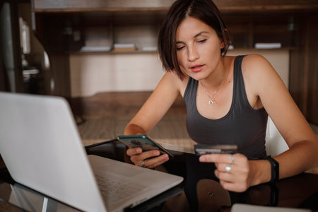 A young asian woman holds a credit card and uses a laptop. The concept of online shopping. black...
