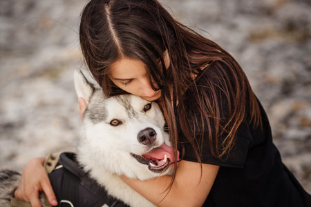 Beautiful girl plays with a dog, gray and white husky, in the mountains at sunset. Indian girl and her wolfの写真素材