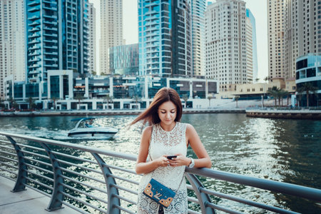 Happy beautiful unrecognizable tourist woman in fashionable summer white dress enjoying in Dubai marina in United Arab Emirates. Luxury and comfortable tourism season in UAE.の写真素材