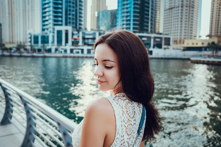 Happy beautiful unrecognizable tourist woman in fashionable summer white dress enjoying in Dubai marina in United Arab Emirates. Luxury and comfortable tourism season in UAE.の写真素材