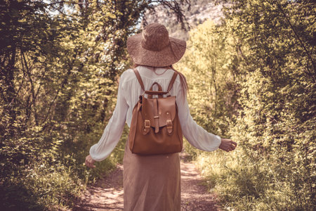 woman traveler with backpack and hat walking in amazing mountains and forest, wanderlust travel concept, space for text, atmospheric moment. earth dayの写真素材