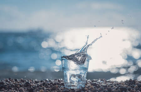 splashing water in a glass by the sea. Beautiful glass with ice and pure mineral waterの写真素材