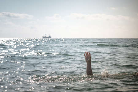 single hand of drowning man in sea asking for help. sticking out of the waterの写真素材