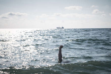 single hand of drowning man in sea asking for help. sticking out of the waterの写真素材