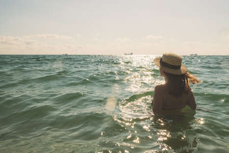 Beautiful young woman in bikini on the sunny tropical beach relaxing in water. soft colorsの写真素材