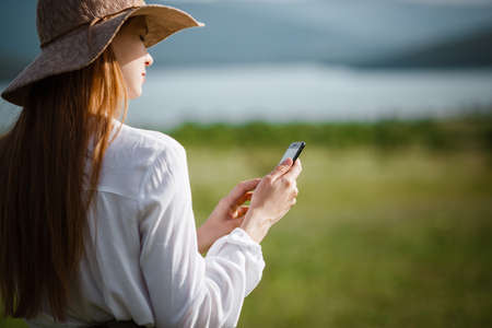 Woman using mobile phone at outdoor. Using a smartphone to navigate the route search, making photos and selfiesの写真素材