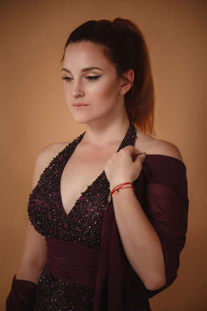 Beautiful young woman in purple dress posing in studio. Classic make-up for the evening eventの写真素材