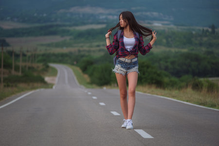 women is hailing a car on a road. Thumbing a ride. Outdoors vacation. Asian