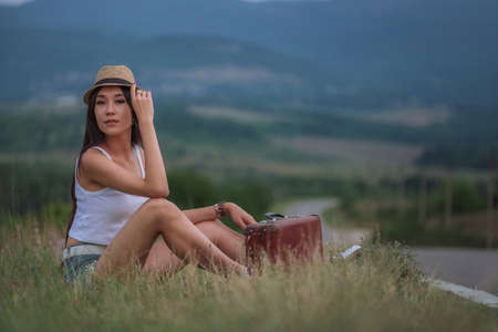 women is hailing a car on a road. Thumbing a ride. Outdoors vacation. Asianの写真素材