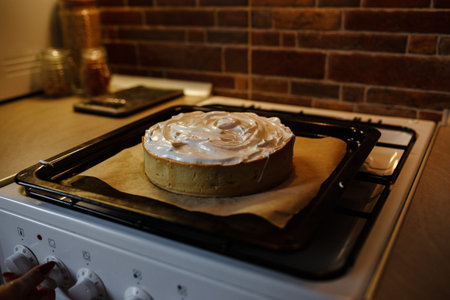 Lemon meringue pie on cutting board on brown wooden background. Preparation of lemon tart.