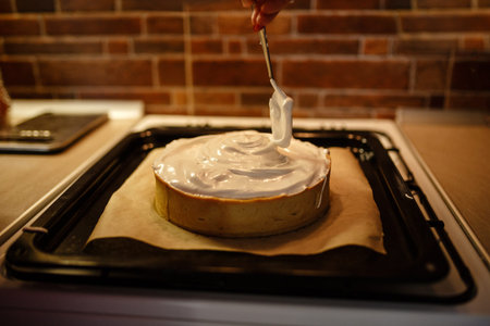 Lemon meringue pie on cutting board on brown wooden background. Preparation of lemon tart.