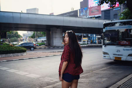 Summer sunny lifestyle portrait of young stylish hipster woman walking on the street, wearing cute trendy outfit. Young Asian women tourist traveler smiling in bangkok. street fashionの写真素材