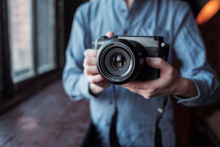 MOSCOW, RUSSIA - 14 MARCH 2019: Fujifilm GFX50s Camera, Fujifilm Mirrorless. Close-up of hand holding camera. Mirrorless camera close up in the hand of a young man on a studio background.のeditorial素材