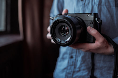 MOSCOW, RUSSIA - 14 MARCH 2019: Fujifilm GFX50s Camera, Fujifilm Mirrorless. Close-up of hand holding camera. Mirrorless camera close up in the hand of a young man on a studio background.のeditorial素材