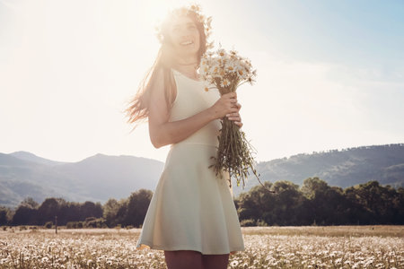 Beautiful young girl smiling over chamomile field. Carefree happy brunette woman with healthy long hair having fun outdoor in nature.の写真素材