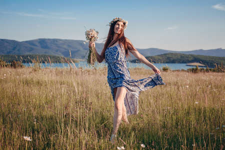 Beautiful woman enjoying field, pretty girl with long dark hair relaxing outdoor, having fun, holding plant, happy young lady and spring green nature, harmony conceptの写真素材