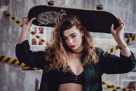 Rock chick theme. Attractive white female long blonde hair wearing jeans and a black top with thin straps, a young rebel and a musicianの写真素材