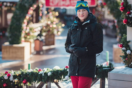 happy young woman in ski goggles outdoors. winter vacation concept. Christmas decorations in a small...