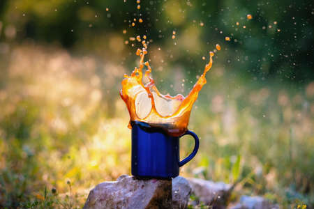 Blue mug of hot tea or coffee with milk, outdoor, Concept adventure active vacations outdoor. Summer camping.の写真素材