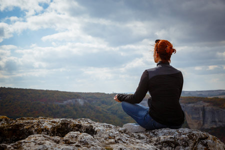 young fitness woman practice yoga at mountain peak cliff edge. women meditating pastel on high mountainの写真素材