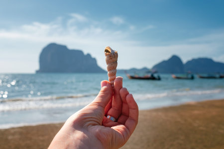 Woman's hand with white beautiful conch shell the cliff of an island in Thailand, Krabi province....