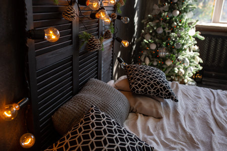 Christmas decor. Bedroom in dark colors with large bed. The interior is decorated with garlands and...