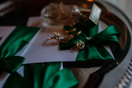 wedding accessories bride on the wedding day. beautiful women's perfume, invitations and rings on a silver tray on the table in the hotelの写真素材