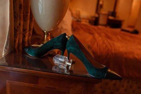 Green Wedding shoes and gold rings on the table in room, accessories bride on the wedding day in warm colorsの写真素材