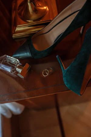 Green Wedding shoes and gold rings on the table in room, accessories bride on the wedding day in warm colorsの写真素材