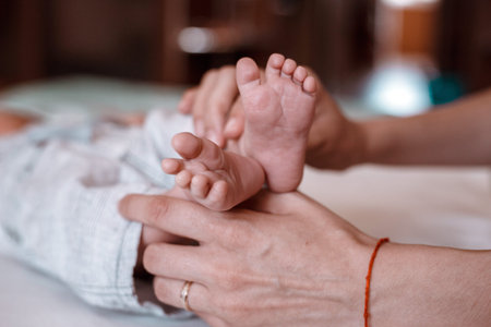 Baby feet in mother hands. Tiny Newborn Baby's feet on female Shaped hands closeup. Mom and her...