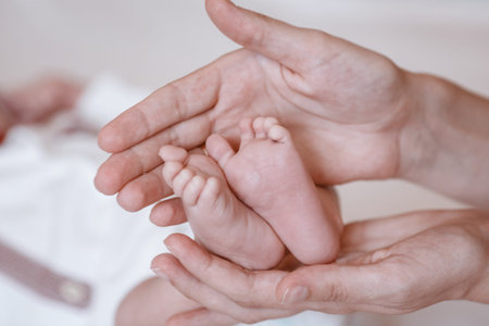 Baby feet in mother hands. Tiny Newborn Baby's feet on female Shaped hands closeup. Mom and her...