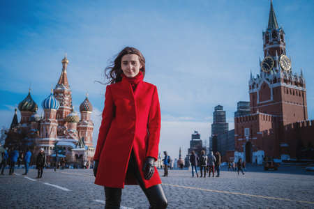 Happy women walking in red coat at the red square in Moscow. Cold time between winter and spring, frost and sunの写真素材