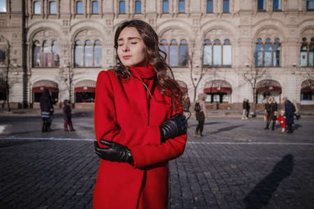 Happy women walking in red coat at the red square in Moscow. Cold time between winter and spring, frost and sunの写真素材