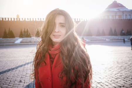Happy women walking in red coat at the red square in Moscow. Cold time between winter and spring, frost and sunの写真素材