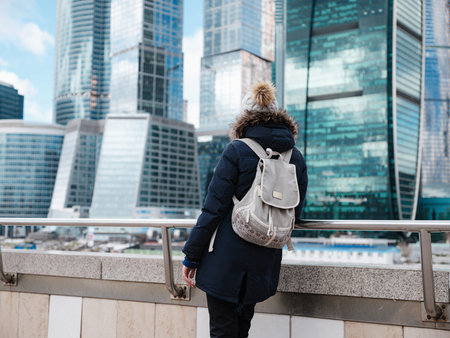Young beautiful woman and Moscow City international business center in the background. Cold Winter...
