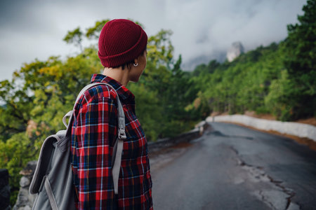 A woman hiker with a backpack enjoying a view of the mountains in the fog. Traveling in the...
