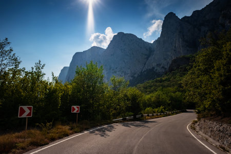 asphalted road in the mountains, beautiful sunshine, summer vacation time. Vintage toning. Travel background. Highway in european mountainsの写真素材