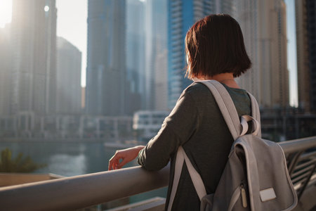 Happy young female traveler in the big city of Dubai, famous place Dubai marina. Luxury and...