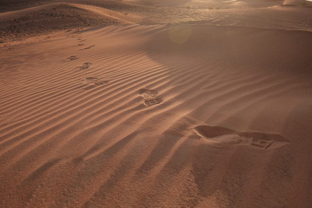 Sunset over the sand dunes with footprints in the desert. The ghost town of Al-Madam is about 60 km from Dubai City. united arab emirates. The concept of global warmingの写真素材