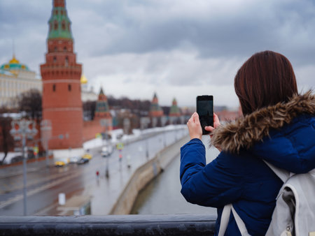Young asian beautiful woman tourist taking pictures on mobile phone on the background of Moscow Kremlin, Russiaの写真素材