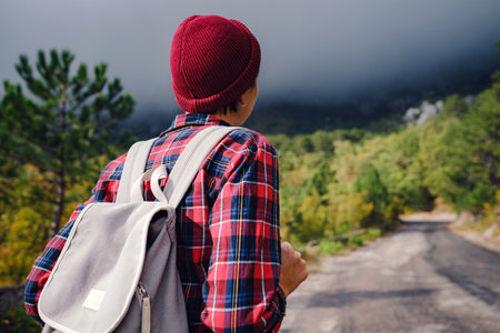 Happy young woman with backpack exploring misty mountains. Travel and wanderlust concept. Amazing atmospheric momentの写真素材