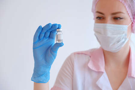 Female doctor in pink uniforms and blue gloves holding vaccine. mock-upの写真素材