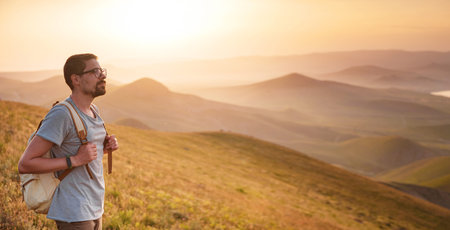 Young sporty man with backpack standing on the top of rock and looking at the seashore and mountains...