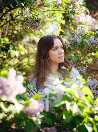 Beautiful Woman Enjoying the Smell of Lilac. Cute Model plus size and Flowers. Aromatherapy and Spring Conceptの写真素材